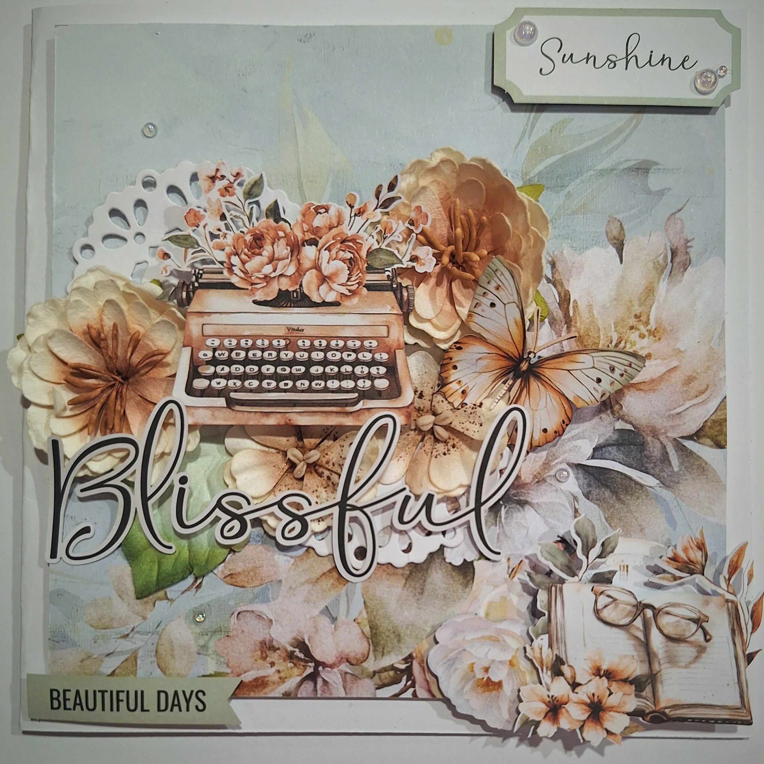 Decorative paper with typewriter, flowers, and butterfly, featuring the word 'Blissful'.