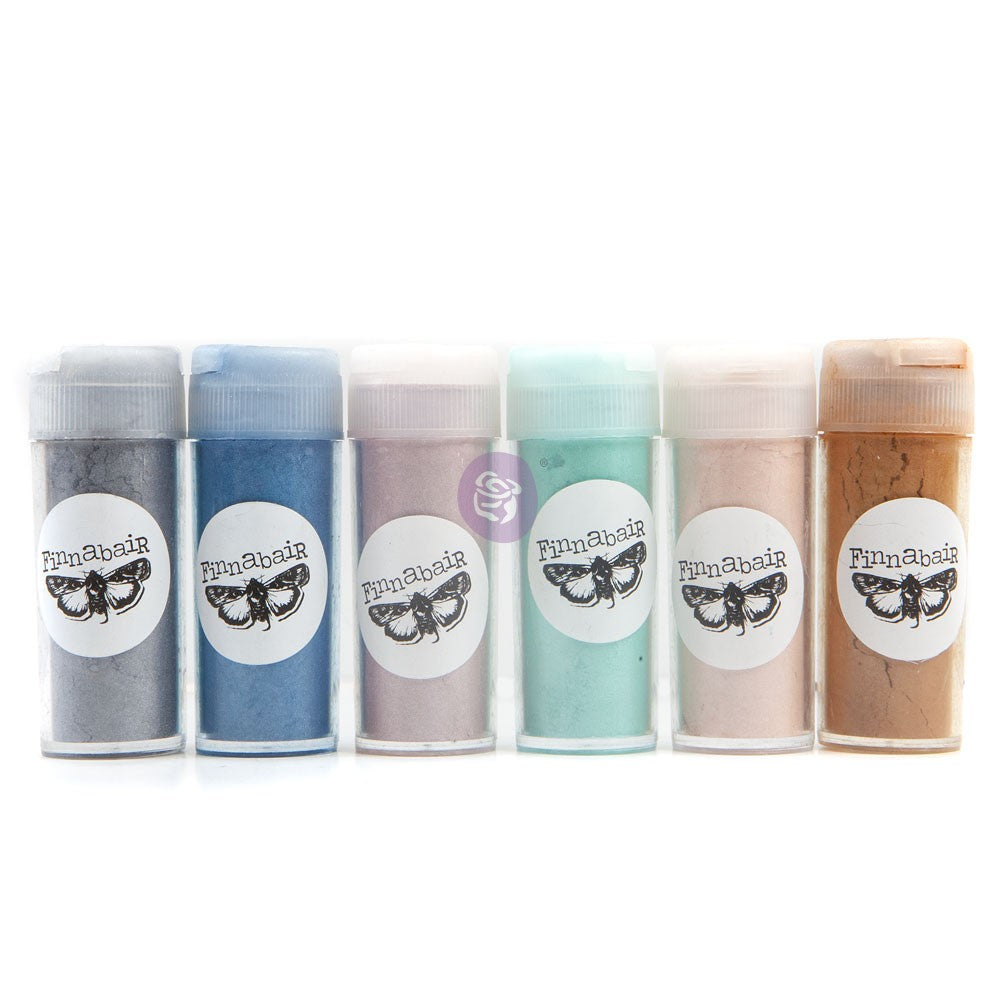 Six small plastic jars of craft mica powder arranged in a row on a white background. The glitter colors are dark gray, medium blue, dusty pink, mint green, pale peach, and warm tan.