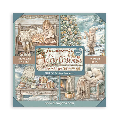 A square product card for Stamperia White Christmas scrapbooking single faced sheets, showing a collage of holiday-themed illustrations including a child reading by a window, a child in a snowy landscape, a decorated Christmas tree, and a teddy bear in a cozy chair. The central label reads 'Stamperia White Christmas' with size and material details, and the website www.