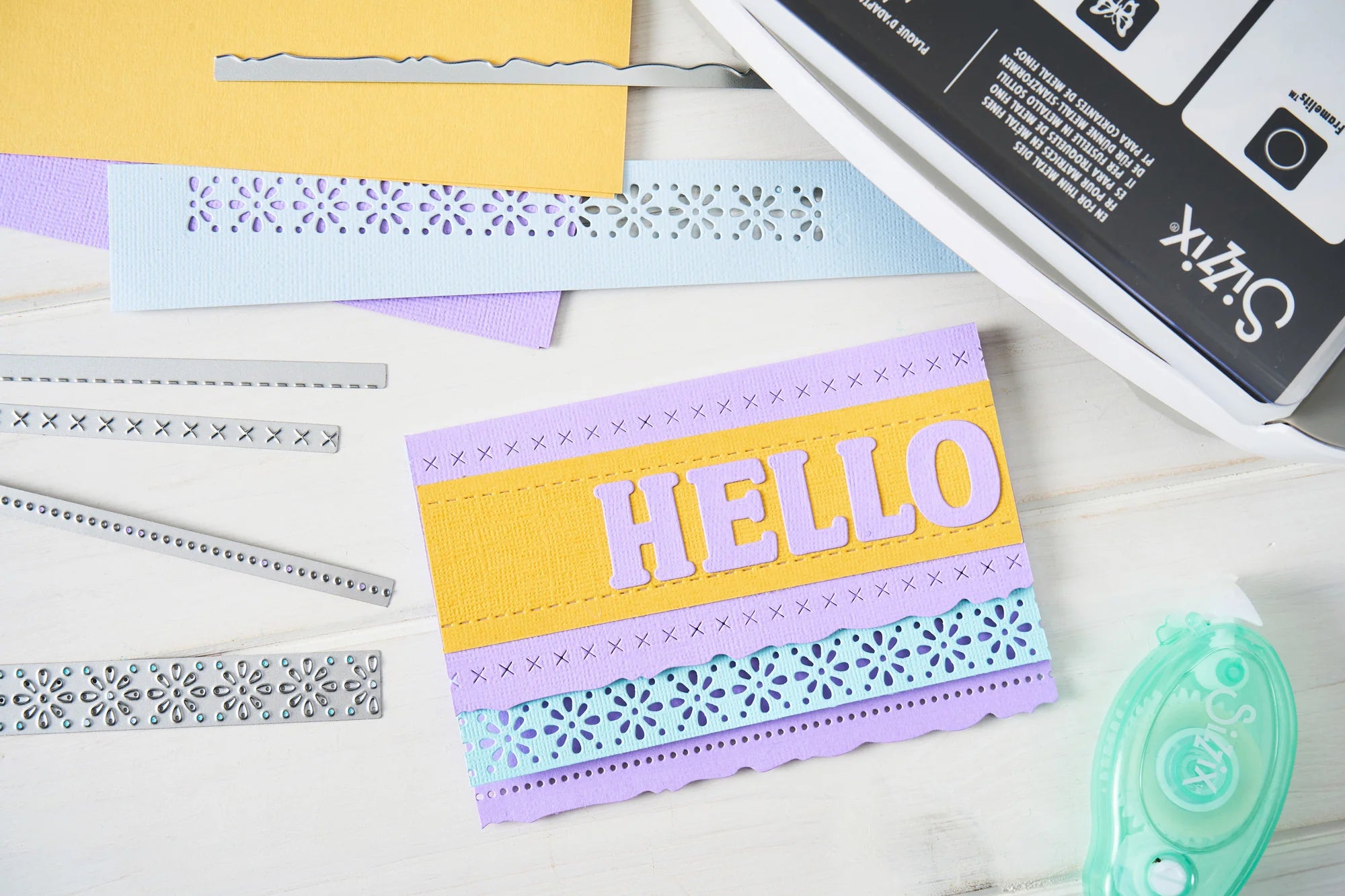 Colorful card with 'HELLO' text on a white surface with crafting tools.