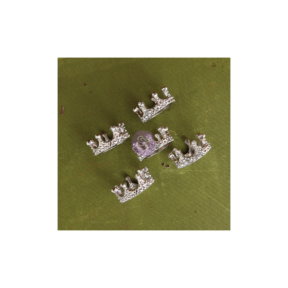 Four silver crown-shaped jewelry charms with clear rhinestones, arranged on an olive green textured fabric background.