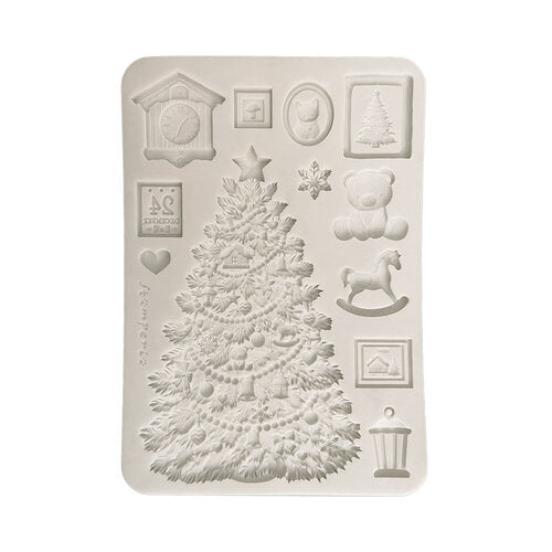 A rectangular silicone mold with embossed Christmas-themed designs, including a large decorated Christmas tree, a teddy bear, a rocking horse, a cuckoo clock, snowflakes, and small framed motifs, shown on a plain white background.