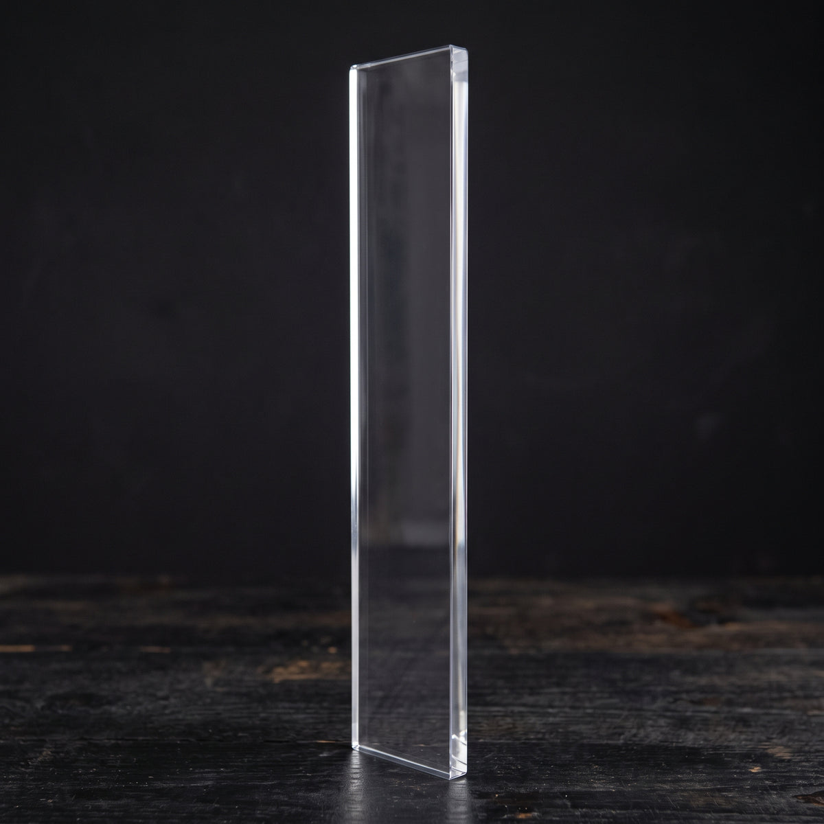 Darkroom Door clear acrylic stamping block, 315 × 65 × 10 mm, standing upright on a dark wooden surface