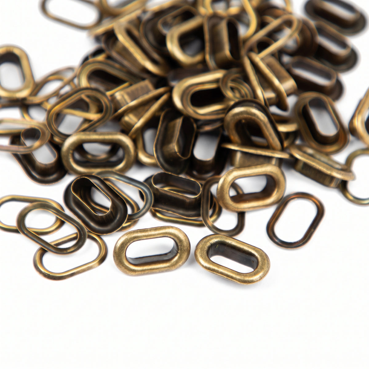 We R Makers copper oval eyelets shown loose from multiple angles on a white background
